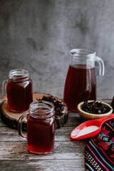 Agua de Jamaica or roselle mocktail drink, summer beverage in mexico with ice and dry hibiscus petals on table background	
