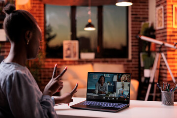 Online business meeting with coworkers, remote team brainstorming on teleconference. African american businesswoman chatting with colleagues on videconference using laptop, back view