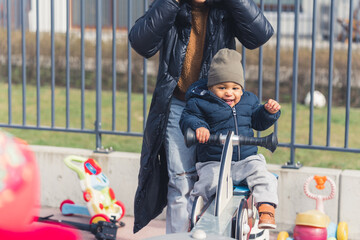 Caucasian mother at the playground with her cute african american son having fun on a see-saw surrounded by children's toys - closeup. High quality photo