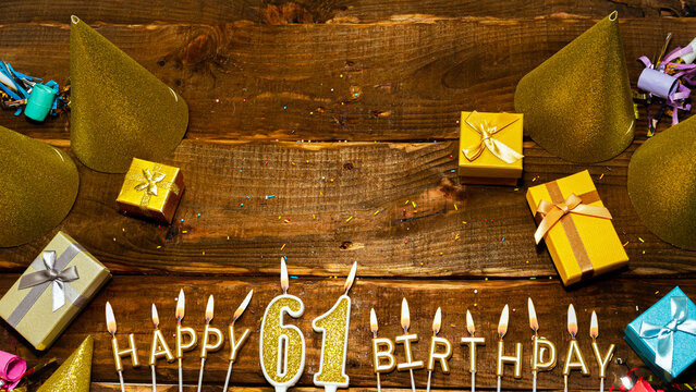golden letters of the candle with the number happy birthday, the background of the gift boxes with candles happy birthday on the background of brown boards. Copy spacePostcard Happy birthday 61