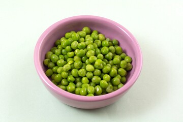 Green peas in pink ingredient bowl on light green background 