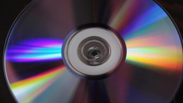 Aged cd spinning close up, obsolete digital storage medium, single multimedia object, light refraction colorful stripes