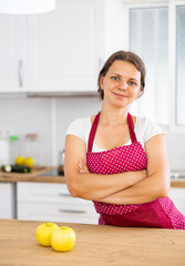 Portrait of woman in apron posing near table in light kitchen