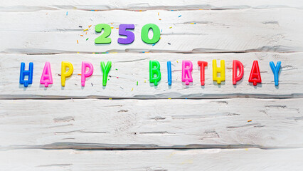 Top view of happy birthday candle numbers copy space on wooden white pastel boards. Beautiful birthday card with number 250