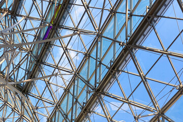 Geometric metal structure with glass, ceiling in a shopping center against the sky