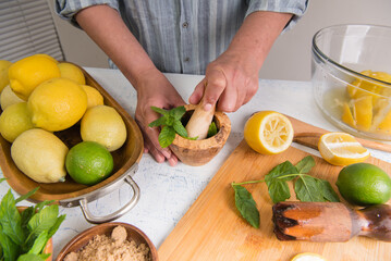 Hands crush mint with a pestle in a mortar. Making majitos or homemade lemonade.