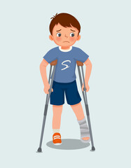 cute little boy has broken fracture leg with bandage cast on leg walking using crutches