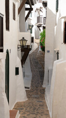 between streets of white facades in the fishing village, Menorca. - 520912215