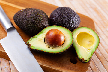 Ripe juicy avocado lying on a cutting board on a wooden surface. Ingredients for cooking