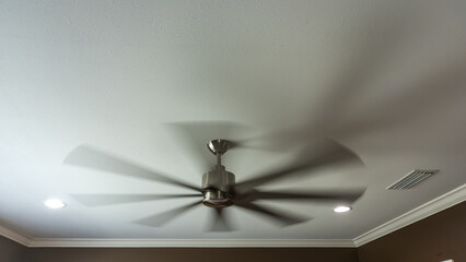 A moving and blurred interior fan inside a new construction house with a white ceiling