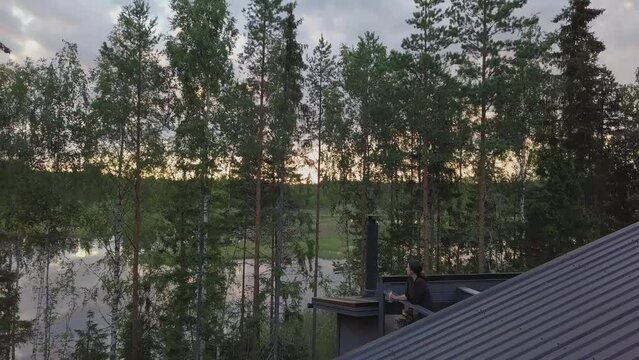 AERIAL shot of woman enjoying view at Nordic summer cabin, scandinavian quality of life concept