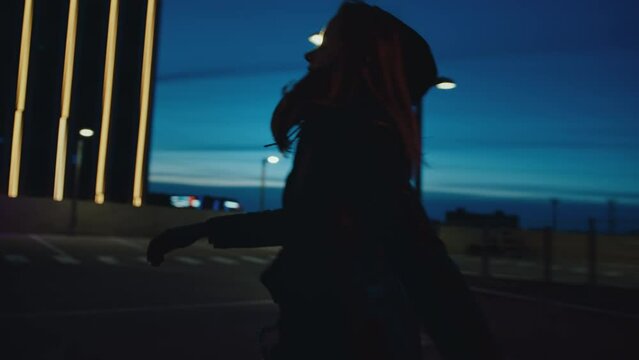 Hooded woman runs on rooftop parking lot, looks over edge