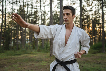 one caucasian man karateka training karate in forest in day in nature