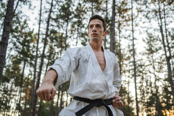 one caucasian man karateka training karate in forest in day in nature