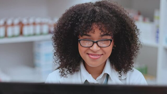 Happy and cheerful pharmacist looking at the stock system and taking inventory in a pharmacy. Female chemist manager smiling while recording medical supply stock take on a computer in a drugstore