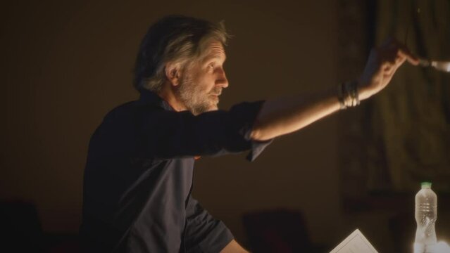 The director in the theater giving recommendations about acting to the actors and reading the script during the rehearsal of the performance