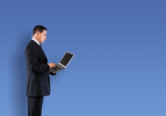 Young business man using laptop computer on blue background