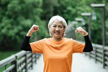 Athletic Senior woman stretching arms in park.