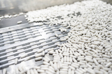 close up view of process production line white capsules supplement, medical industry concept.