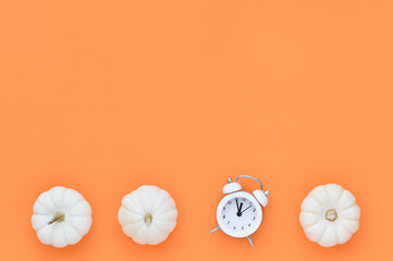 Minimal white mini pumpkins with clock on orange