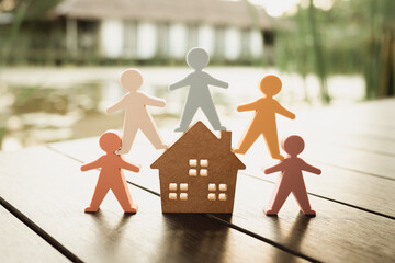 Model of a wooden house and a model of people surround the house.
Concept of happy family, People living and caring for homes, buying, mortgages, and real estate investments.