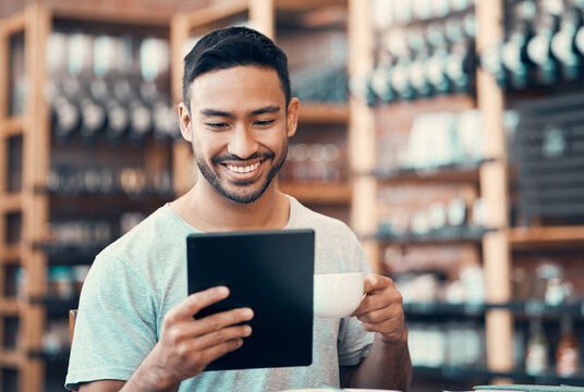 Happy, relaxed and carefree man reading social media news on a tablet while enjoying coffee. Young casual guy replying to emails, browsing the internet or subscribing to online dating app at a cafe