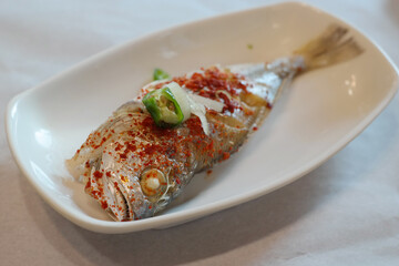 Steamed Yellow Croaker topped with minced garlic, julienned green onion, red chili powder, and sesame seeds and steamed in a steamer. The salty taste and chewy texture of the dish go well with rice.