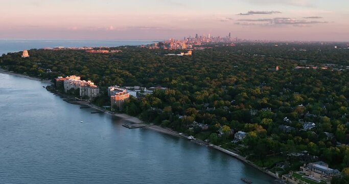 Flying above Chicago North Shore suburbs and Lake Michigan shoreline, late afternoon warm light. Chicago downtown visible on the horizon