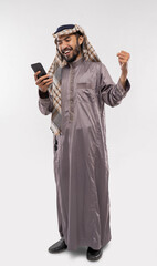 an arabian youth in a turban using a mobile phone excitedly looking at screen raise his arm