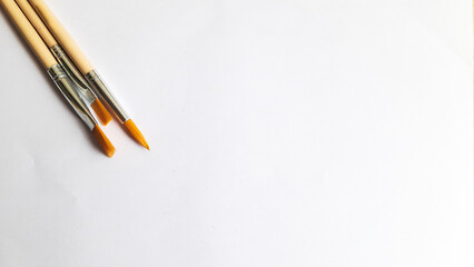 Top view of a variety of artist brushes on a white background with room for text. Creative postcard