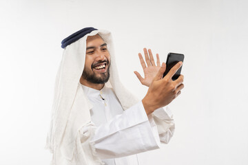 excited young man in a turban using a mobile phone happily looking at the screen waving to partner online