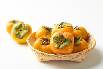 Ripe persimmon fruit in basket on white background