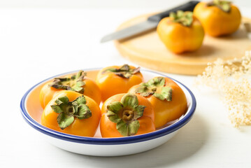 Ripe persimmon fruit in bowl on white background