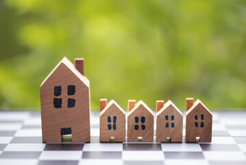 row of wood house mogel on wooden table with green natural leaves background