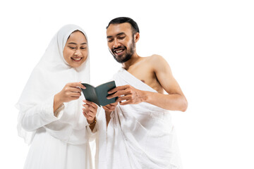 Happy man and woman wearing ihram clothes reading a passport on white background