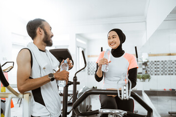 beautiful muslim couple having fun at the gym while enjoying a bottle of water together