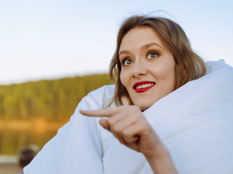 Young Woman In Wrap Cover Blanket Duvet Point Finger Aside On Copy Space Area On Pastel Blue Nature Background