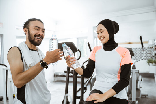 beautiful muslim couple having fun at the gym while enjoying a bottle of water together © Odua Images