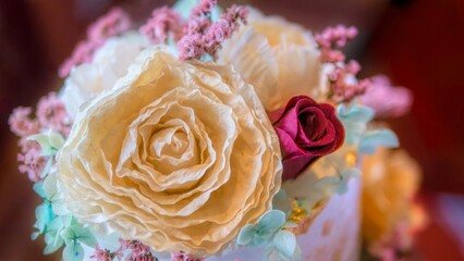 Ethereal, dreamy, and soft focus close up view of artificial flowers on top of a wedding cake.