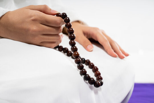 Close up of woman hands praying with prayer beads and prayer rug on isolated background
