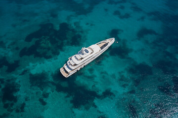 Aerial view White big yacht is anchored on transparent water. Yachts for a millionaire on the water...