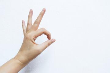 Female hand with ok hand gesture on white cement wall background, sign gesture