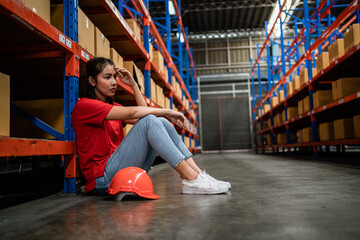 Tired, hot, sad, stressful Asian woman worker in a warehouse. Industrial plants, transportation and delivery of goods. Factory, industry, warehouse