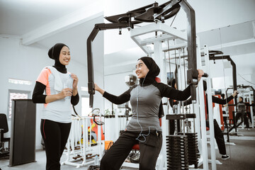 muslim asian woman using chest press machine during fitness at the gym