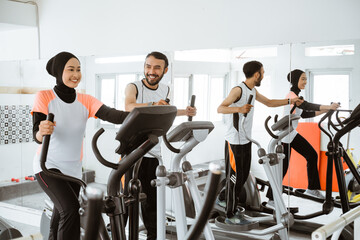 muslim women at the gym doing cardio exercises on static elliptical cycle machine