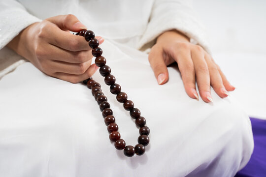 Close up of woman hands praying with prayer beads on isolated background