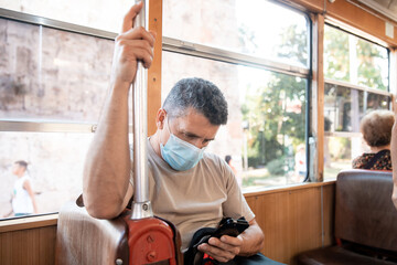 Senior old man on face medical mask while traveling inside public transport, tram Turkey