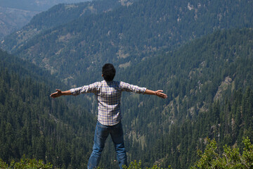 Adventurous guy outstretched arms outdoor himalayan cedar mountain forest in background - obrazy, fototapety, plakaty