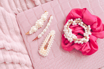 Set of pearl hairpins and elastic bands on pink background