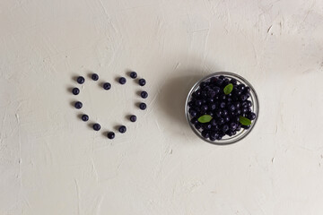 The blueberries heart and fresh blueberries in the clear glass bowl on the white background